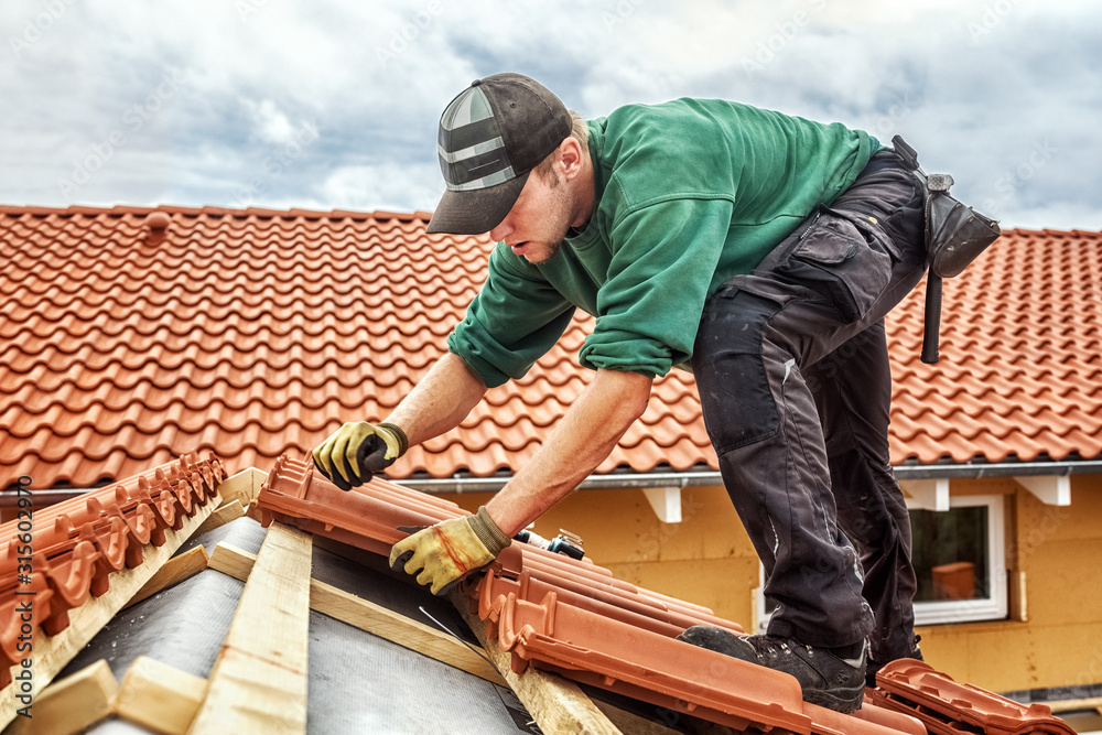 Dachdecker verlegt Dachziegel auf einem Steildach